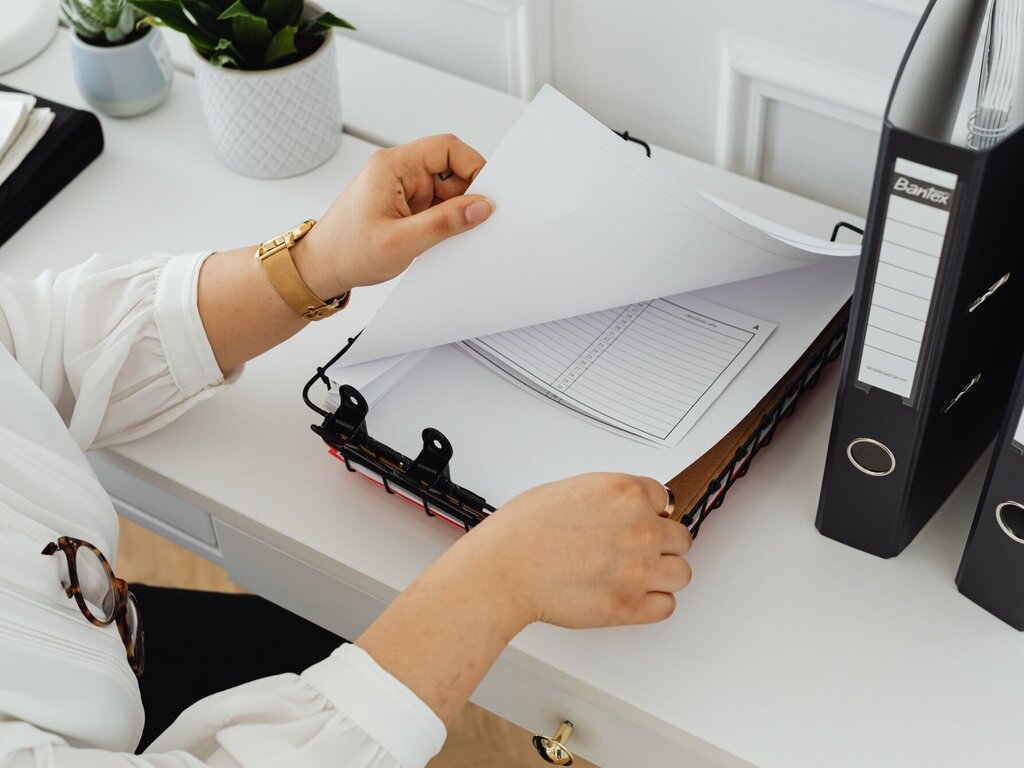 Papers and folders on a white table are leafed through