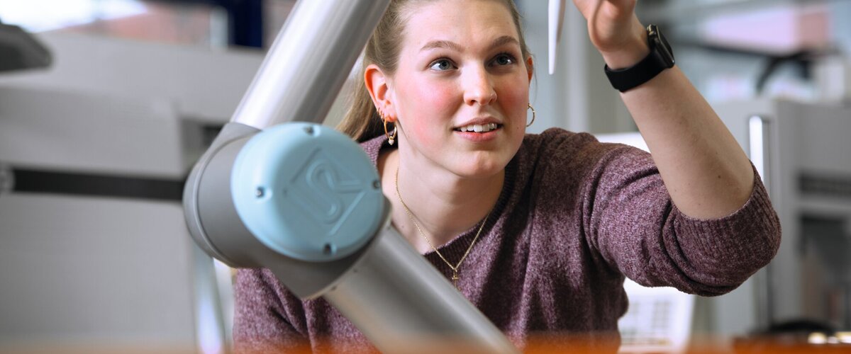 Studentin überprüft das Werkzeug eines Roboterarms im Labor