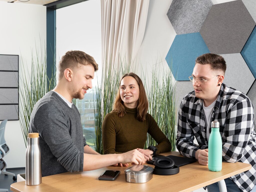 Three students are talking at a bar table in the self-study room