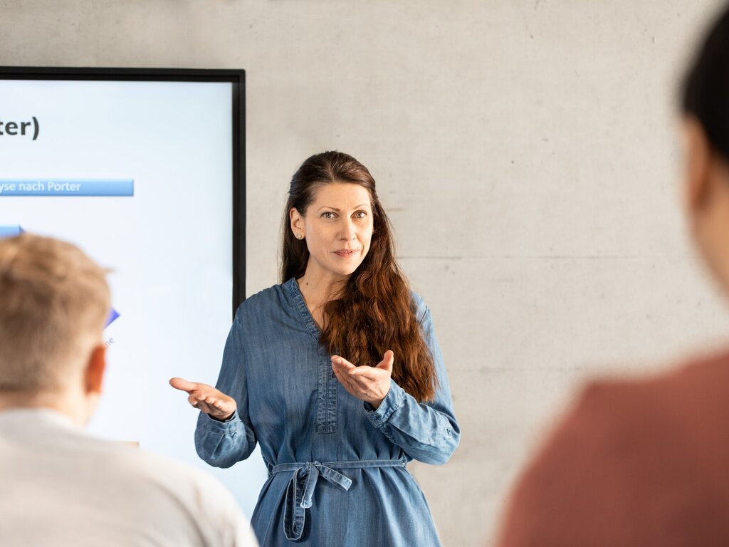 Teacher makes an explanatory gesture towards students