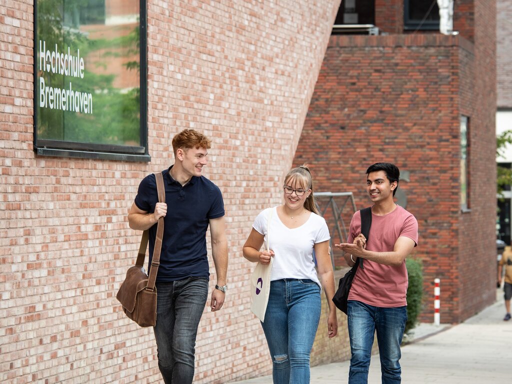 Studierende unterhalten sich während des Laufens auf dem Campus