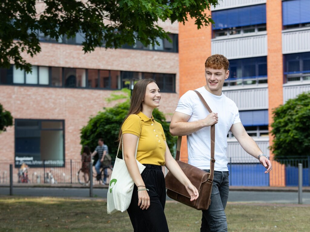 Two student with bags in front of the university