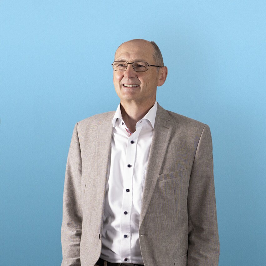 Gerhard Feldmeier stehend vor einem blauen Hintergrund