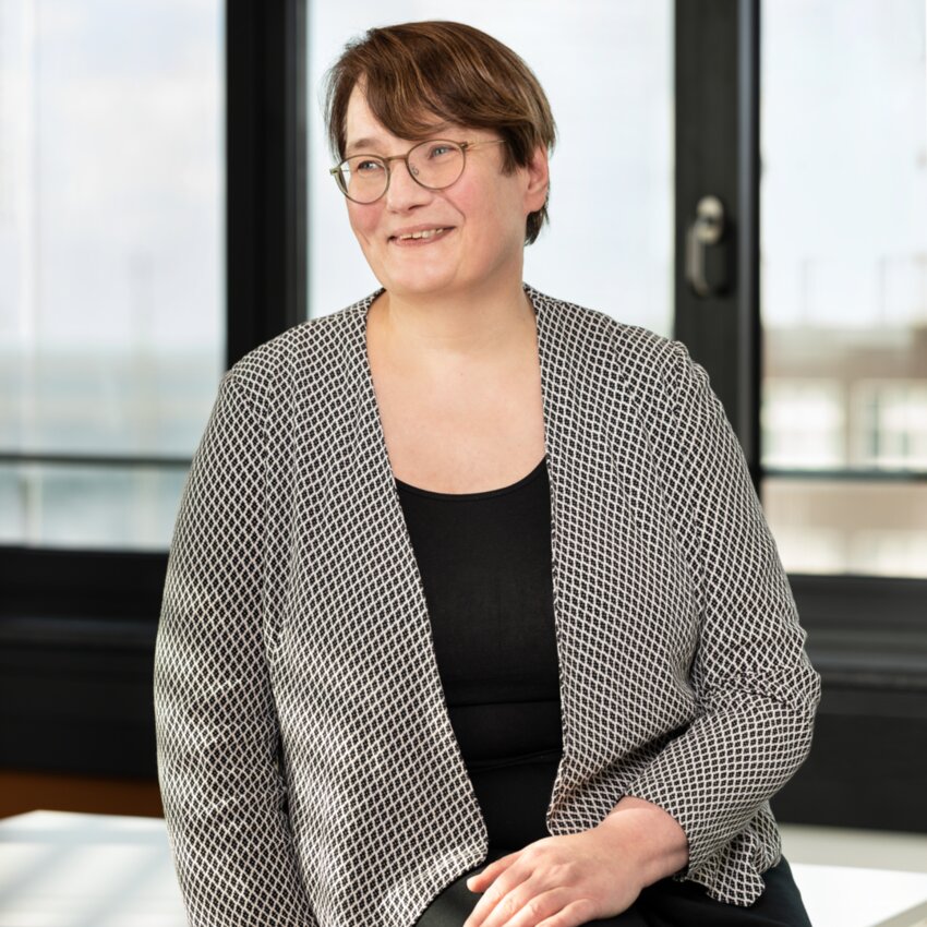 Helga Schiwek sitting in front of a glass front